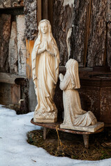 Statue of a Nun Praying in Front of a White Madonna Statue