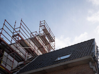 Scaffolding on and next to the roof of an adjacent house to be able to work on the roof of a new building