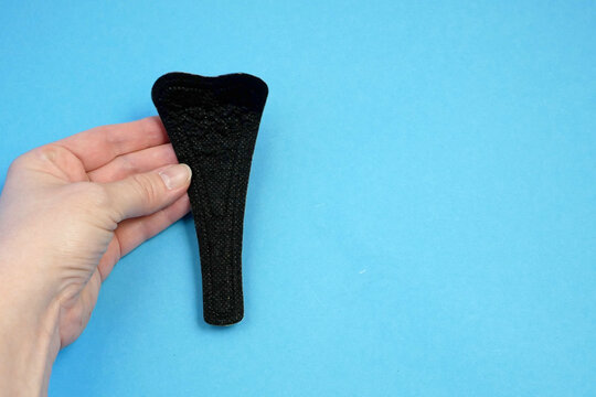 Woman Holding Sanitary  Black Napkin In Her Hand On Blue Background.