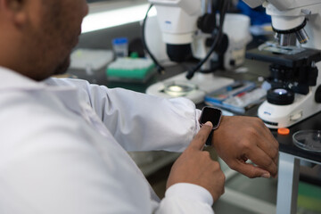 Close-up of a researcher using a smartwatch in a laboratory.