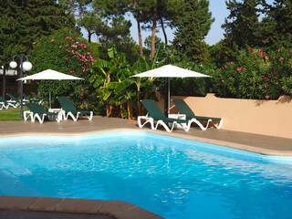 Quiet swimming pool with sunbeds and garden surrounding at Algarve Portugal