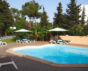 Quiet swimming pool with sunbeds and garden surrounding at Algarve Portugal