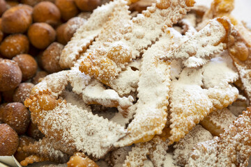 Frappe or chiacchiere and onbaked castagnole typical Italian carnival fritters dusted with powdered sugar. Biscuits with sugar for the carnival of Venice. Traditional sweet pastries of the carnival 
