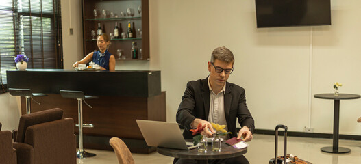 A male traveler enjoys using airline business lounge at a terminal waiting for departure. Business...