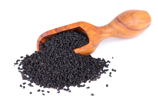Black cumin seeds in wooden spoon, isolated on white background. Heap of black nigella seeds. Nigella sativa.