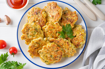 Chicken cutlets made from minced meat, onion, garlic and fresh herbs on a plate on a white wooden background. Top view, selective focus.