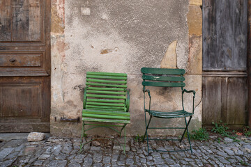 Old green chairs in the street against a wall