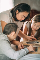 Young asian woman with a girl and elderly woman with Down syndrome looks at photos in an old album....