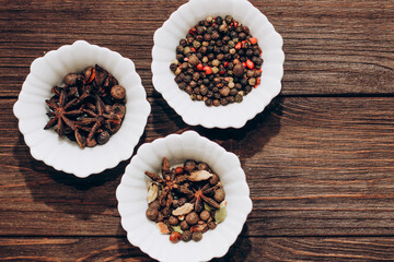 Spices anise, pepper, cumin, cumin, ginger in bowls on a wooden table.