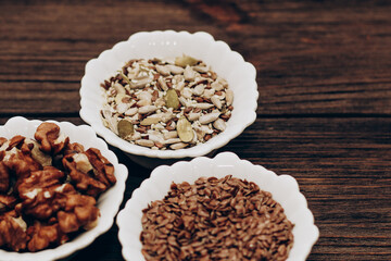 A mixture of sunflower, pumpkin and flax seeds with nuts in a bowl on a wooden table.