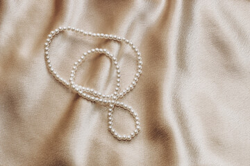 Pearl bijouterie beads on silk texture background.