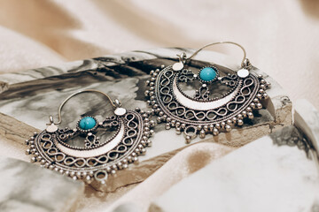 Ethnic stylish jewelry earrings on a silk golden background.