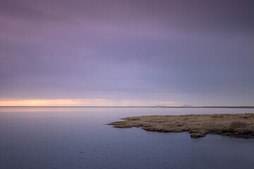 Fototapeta premium Tranquil landscape on a lake in Iceland at sunset with a mountain in the background and bluish tones