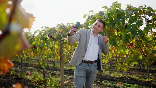 Well-dressed entrepreneur taking picture of his young vine, proud of it. Commercial video. 4K.
