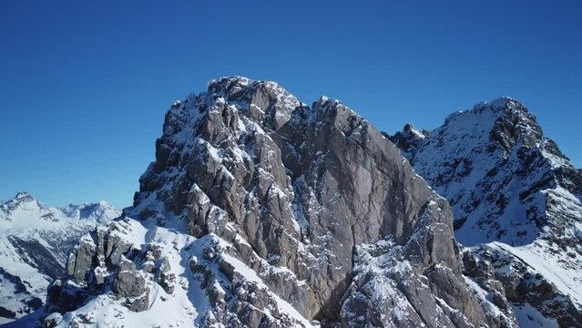 Fly around alpine mountain covered in snow