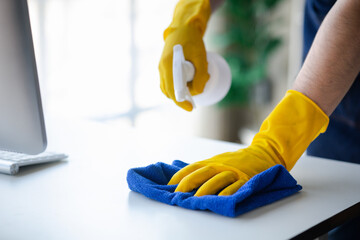 Person cleaning the room, cleaning staff is using cloth and spraying disinfectant to wipe the glass in the company office room. Cleaning staff. Maintaining cleanliness in the organization.