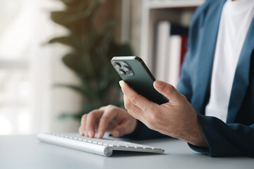 Fototapeta premium Business man looking at financial information from a mobile phone, he is checking company financial documents, he is an executive of a startup company. Concept of financial management.