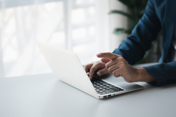 Person typing on laptop keyboard and pointing at screen, businessman working on laptop, he is typing messages to colleagues and making financial information sheet to sum up the meeting.