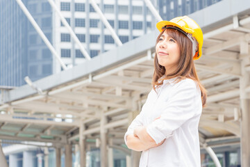 Young architect woman in yellow helmet standing at the city, Female engineer at building construction site