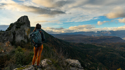 Jeune femme contemplative devant la montagne en Cévennes, équipée pour la randonnée d'automne