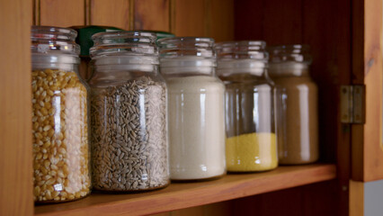 Glass jars in pantry full of spices and food