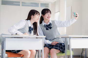 教室で仲良く自撮りをする2人の女子高生
