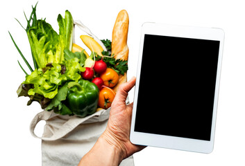 Online shopping mobile app holding by a hand with blurred background of fresh vegetables and...