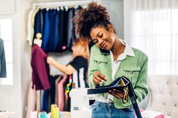 Portrait of young african american woman fashion designer stylish sitting and working with color samples.Attractive young african girl work with colorful fabrics at fashion studio