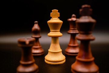 white king between black pieces in checkmate with black background, chess