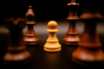 white pawn between black pieces with black background
