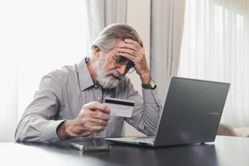 Upset senior elderly man holding credit card by laptop having trouble worry finance safety data or online payment security. Bank client concerned about problem with credit card, financial fraud threat - obrazy, fototapety, plakaty