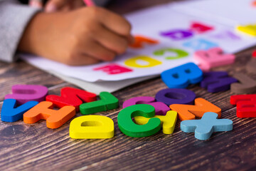 English alphabet made of square wooden tiles with the English alphabet scattered on hand. The concept of thinking development, grammar