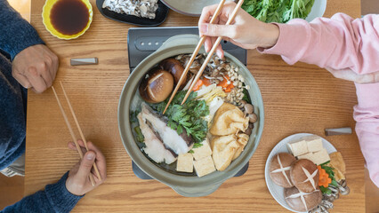 家庭で日本の鍋料理を食べる夫婦　イメージ