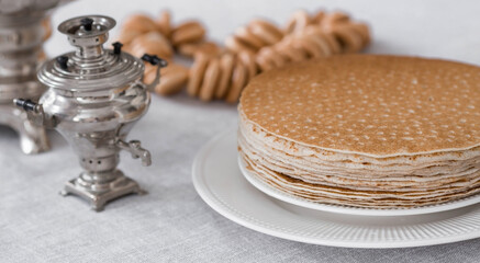 Russian traditions. Russian holiday Maslenitsa. Still life with bagels, a stack of pancakes and a samovar on the table.