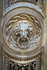 Fototapeta na wymiar Antique decorative handle knocker on wooden vintage house door. Classical metal bronze lion head 