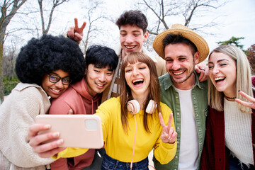 Group of smiling international teenage friends taking a selfie with Mobile cell in an urban park in...