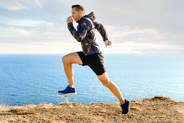 male runner in windbreaker running in background sky and sea © sports photos