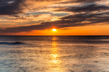 Fototapeta premium Colorful sunset on the Baltic Sea in Rowy, Poland. Landscape with waterbreak in the sea under the sky at sunset.