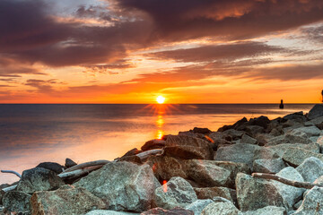 Colorful sunset on the Baltic Sea in Rowy, Poland. Landscape with waterbreak in the sea under the sky at sunset.