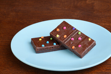 chocolate brownies with candy pieces on a plastic blue plate