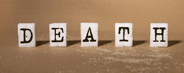 Death word on refines white sugar cubes, pieces. Excessive consumption, sweet addiction concept