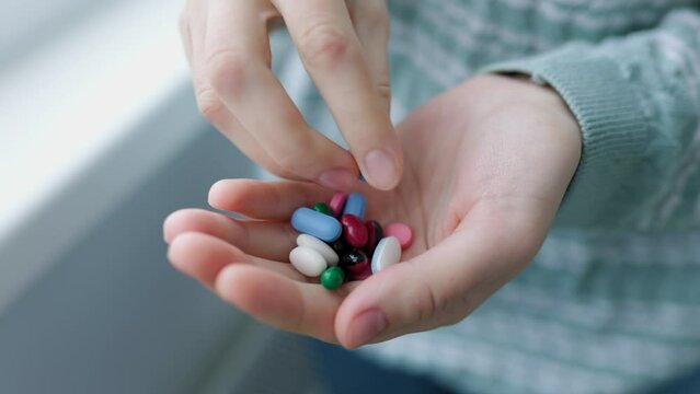 Top view unrecognizable handful of tablets close up in woman palm, girl takes one pill to drink it. Nutrients. Pills. Health.