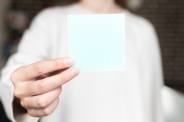 woman is holding a square empty blank sticker in her hands. Background space for text or advertising or reminder