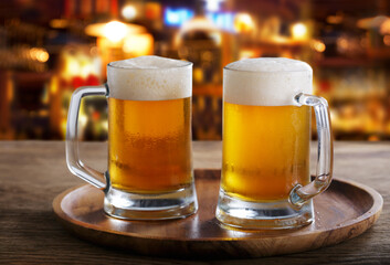Two mugs of beer in a bar on wooden table