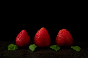 Close up image of raw strawberries on black background.