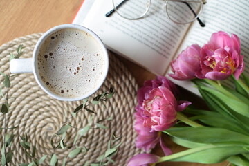 Coffee latte, open book and tulips on wooden table