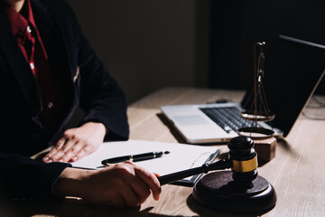 Justice and law concept.Male judge in a courtroom with the gavel, working with, computer and docking keyboard, eyeglasses, on table in morning light