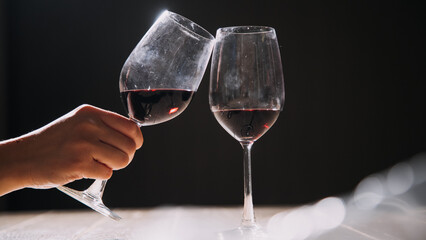 Set of hands holding red wine glass isolated on black background.