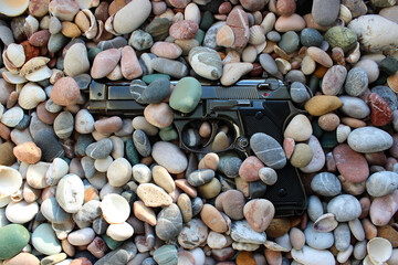 A gun sprinkled with small pebbles on a sea beach in the early morning 
