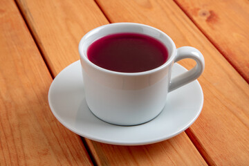 Cup of natural rose hip tea on wooden table